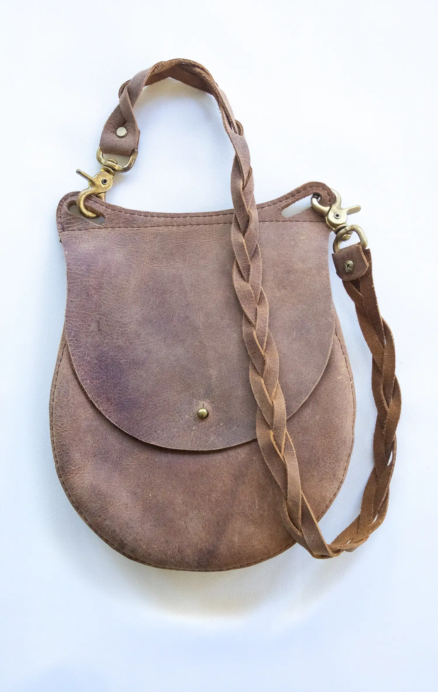 A tan leather shoulder bag with a removable woven shoulder strap and bronze hardware displayed against a neutral background.